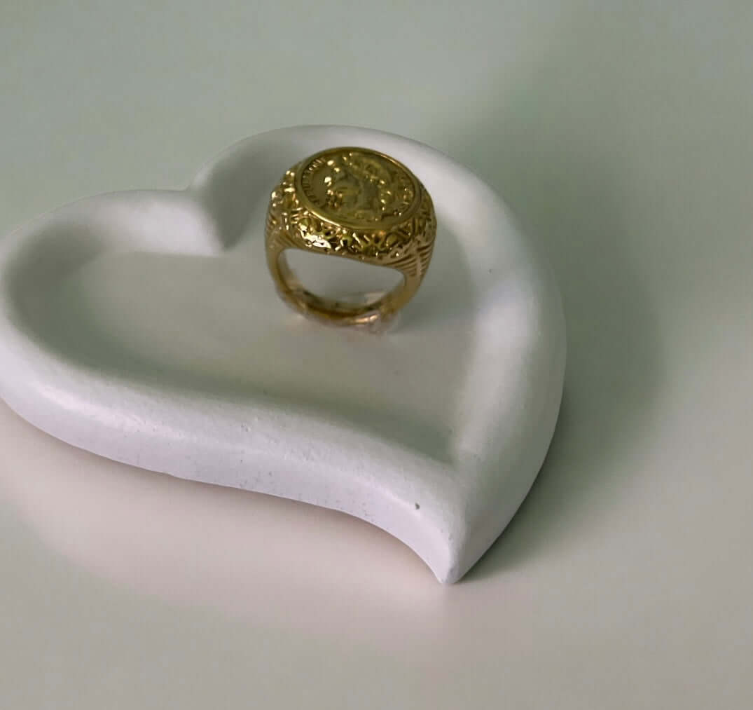 Bague femme dorée vintage sur un plateau en forme de cœur, motif élégant et raffiné.